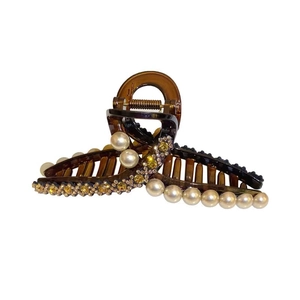 Elegant amber claw clip with inlaid pearls and sparkling rhinestones on white background