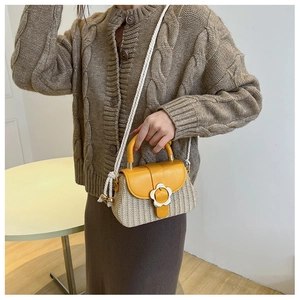 Détail de la boucle fleurie argentée sur le rabat en cuir jaune du sac en paille