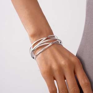 Detailed view of layered silver geometric crossover cuff bracelet on female wrist