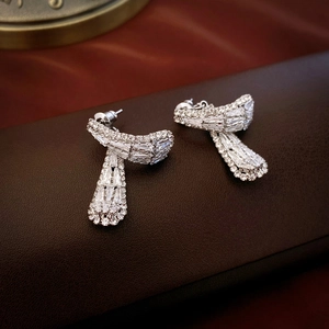 Detail view of streamlined silver earrings with pavé zircon on dark leather