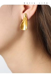 Close-up of minimalist geometric gold-plated titanium earrings worn by a model