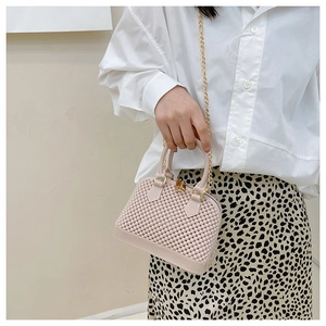 Pink shell jelly bag with woven texture and gold chain strap worn by a female model