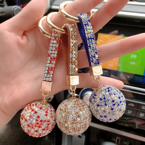 Detailed view of three luxury rhinestone ball keychains with leather straps in hand