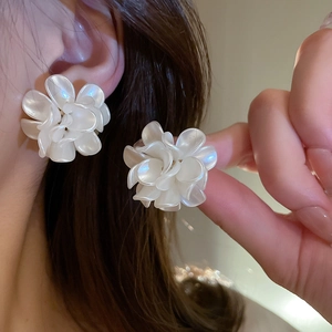 Elegant white acrylic flower earrings with pearly finish worn on a female model