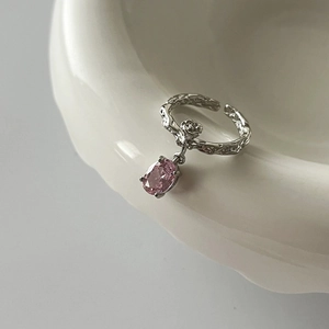 Detail of silver textured ring featuring a pink zircon pendant and rose relief motif