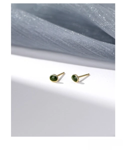 Dettaglio di orecchini a lobo avocado in argento S999 su elegante seta blu chiaro