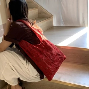Detail of red hollow crochet knit hobo bag showing retro geometric weave and texture