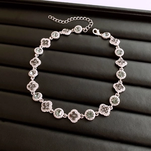 Détail du collier vintage argenté avec pendentif fleur, pierres vertes et diamants