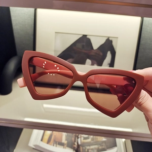 Detailed close-up of retro cat-eye sunglasses with red matte frame and brown lenses