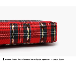 Detail showing precise stitching and red plaid fabric texture on a baguette bag