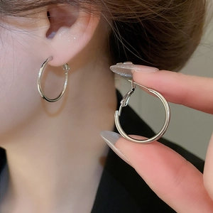 Close-up of polished silver hoop earrings with latch back closure on model's ear