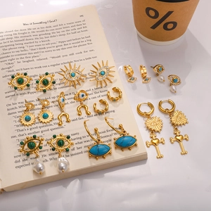 Detailed view of gold evil eye earrings set with turquoise and pearls on an open book