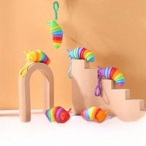 Rainbow-colored articulated slug toy with plastic hook on a minimalist display stand