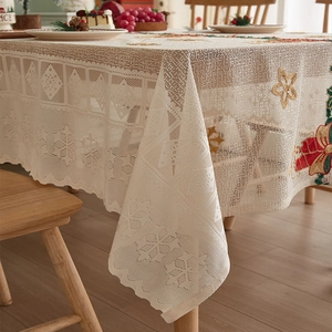 Detail of beige lace tablecloth featuring golden flower embroidery and hollow patterns