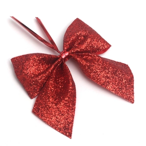 Detail of red glitter Christmas bow ornament with gold wire tie for holiday decoration