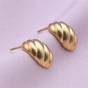 Macro shot of gold-plated stainless steel croissant earrings on soft purple fabric