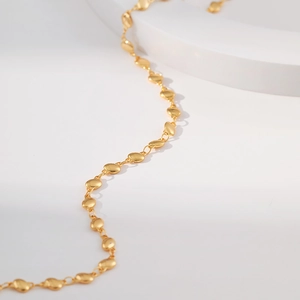 Macro detail of 18K gold plated oval bean link chain on a minimalist white display