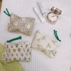 Three-piece floral cotton pouches set with green zip pulls on a soft white background