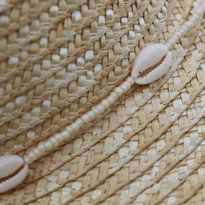 Dettaglio della trama di cappello di paglia con perline e conchiglie naturali