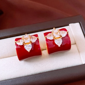 Gros plan de boucles d'oreilles fleurs en émail rouge et zircons dans un écrin de luxe