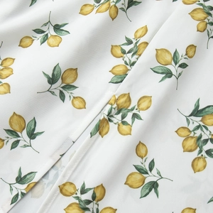 Detailed close-up of vibrant lemon print on white fabric with fine stitching quality