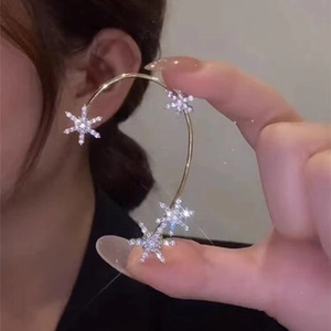 Macro shot of gold ear cuff featuring multiple sparkling rhinestone snowflake designs