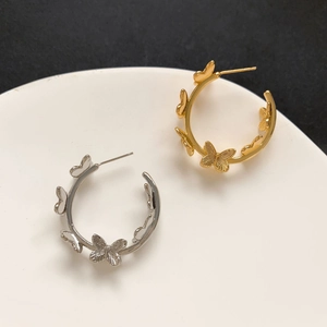 Detail view of gold and silver butterfly hoop earrings on a white ceramic plate