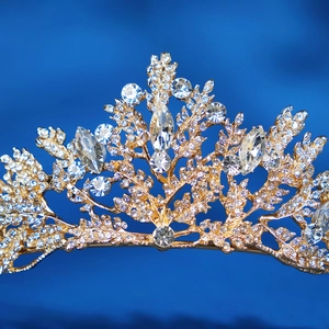 Elegant gold bridal tiara with crystal leaves and rhinestones on a dark blue background
