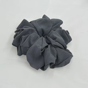 Detailed view of a dark grey oversized chiffon scrunchie with soft pleated fabric texture