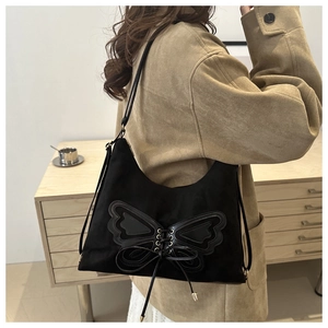 Detail of black matte shoulder bag featuring large leather butterfly patch and lacing