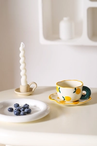 Macro shot of hand-painted lemon pattern on cream ceramic coffee cup and saucer set