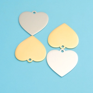 Polished 33mm heart-shaped metal pendants in gold and silver finishes on blue background