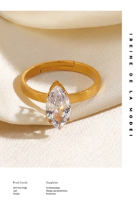 Detail of marquise-cut zircon ring with golden band on elegant cream satin fabric
