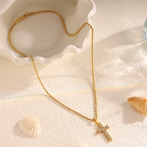 Macro shot of gold cross pendant with cubic zirconia on rope chain and shell decor