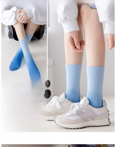Detail of gradient blue crew socks featuring ribbed texture styled with white sneakers