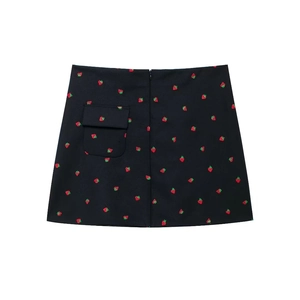 Détail d'une mini-jupe noire en trapèze avec broderie fraise rouge et poche à rabat