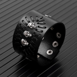 Detail of black wide leather punk bracelet with silver skulls and adjustable snap buttons