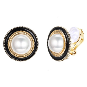 Close-up of gold geometric clip-on earrings with black enamel and white pearl detail