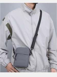 Gray canvas men's crossbody bag with adjustable strap shown on model's shoulder