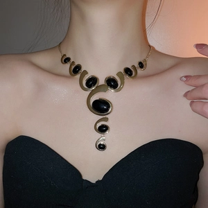 Elegantly styled woman wearing a gold oval tassel necklace set with black gemstones
