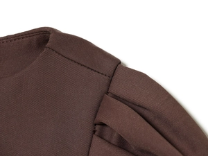 Detailed close-up of pleated shoulder seams and brown woven fabric texture on a short dress