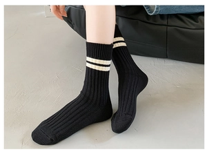 Detailed macro view of black ribbed combed cotton socks with two white varsity stripes