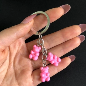 Detailed view of three pink resin gummy bear pendants hanging on a metal keychain held by hand