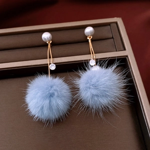Dettaglio di orecchini placcati oro 18K con pompon blu, perla bianca e cristalli lucidi