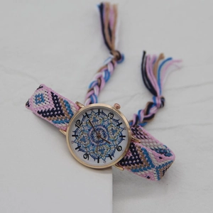 Detail of bohemian woven strap watch with gold case and mandala pattern dial