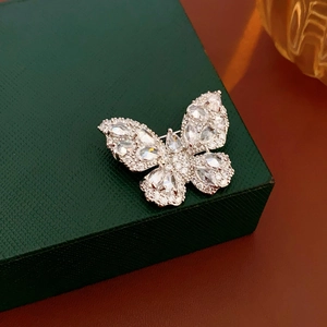 Macro view of silver butterfly brooch with marquise cut zircon stones on green gift box