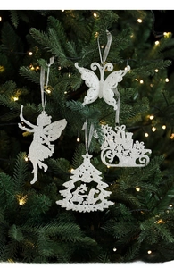 Close-up of white glitter Christmas ornaments including angel and tree on a pine branch