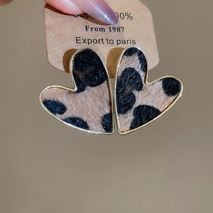 Close-up of leopard print heart earrings with gold edges on a brown display card