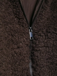 Detailed view of heavy dark brown lamb wool jacket texture with premium metal zipper