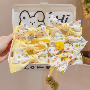 Handheld white box filled with yellow polka dot bow hair clips and scrunchies set